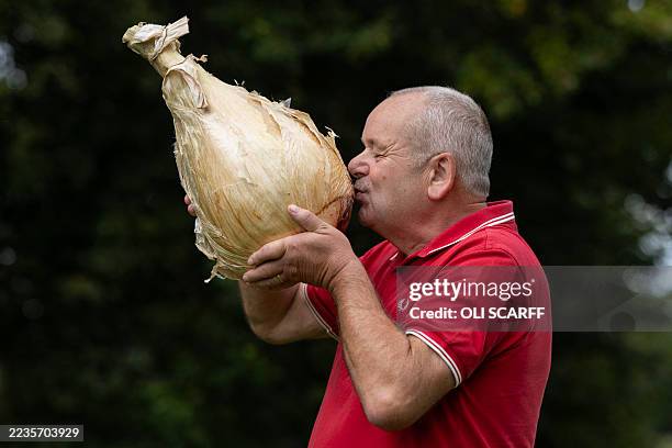 Stephen Purvis poses for a picture with his winning 8.8 kg onion which won the 'Heaviest Onion' category of the giant vegetable competition on the...