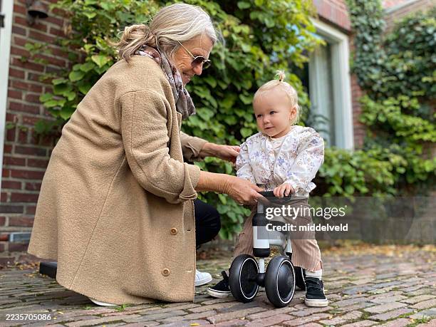 grandmother learning her toddler granddaughte on the toy vehicle. - nanny stock pictures, royalty-free photos & images