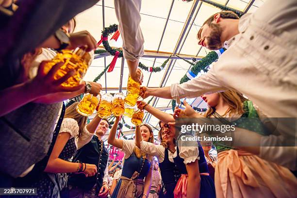 fröhliches bierfest mit freunden in tracht gemeinsames feiern in münchen - oktoberfest stock-fotos und bilder