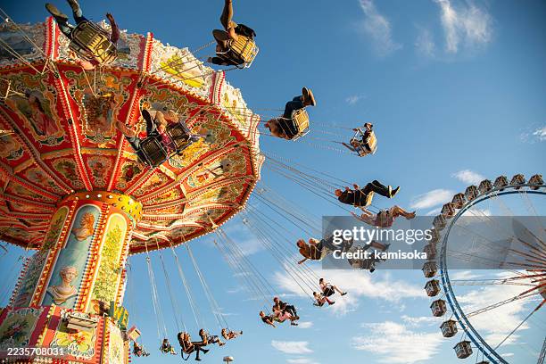 colorful swing ride and ferris wheel at beer fest in munich, germany - draaimolen stockfoto's en -beelden