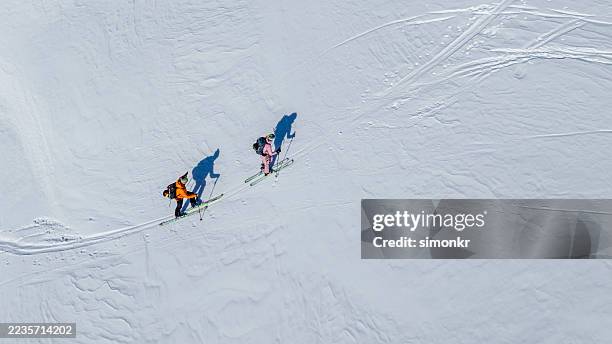 ski enthusiasts navigating alpine terrain at sunrise - skier stock pictures, royalty-free photos & images
