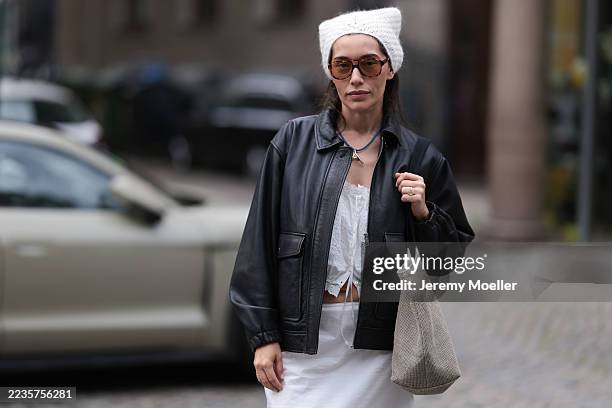 Anna Schürrle seen wearing a white knitted/crocheted wool headscarf, tied elegantly around her head. Her brown hair falls loose underneath, adding a...