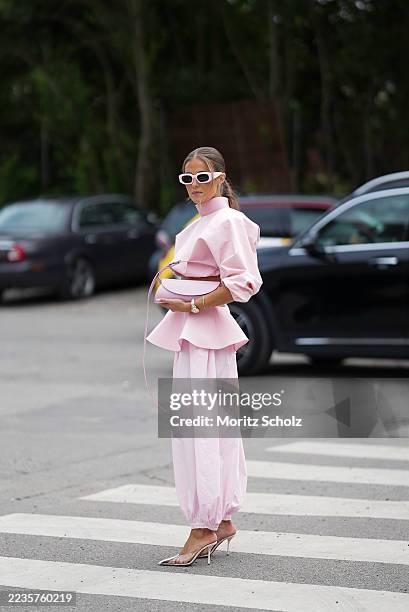 Nina Sandbech is seen wearing a light pink structured top with a high neckline and long sleeves with a peplum detail at the waist; a light pink...