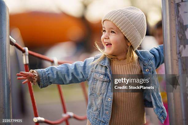 glückliches kind, das spielt und spaß hat auf dem klettergerüst auf dem spielplatz. - kinderspielplatz stock-fotos und bilder