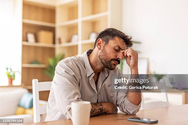 stressed man suffering from headache at home - tired stock pictures, royalty-free photos & images
