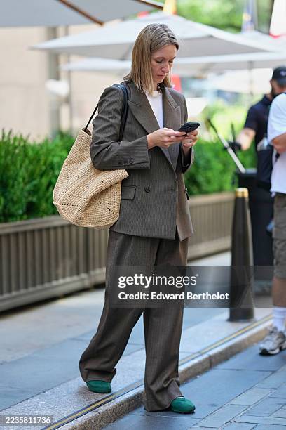 Guest wears shoulder-length straight blonde hair parted in the middle, a short white pearl necklace, a large slouchy woven straw tote with a black...