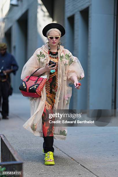 Guest wears platinum blonde hair pulled back into a low bun topped with a black round hat, white cat-eye sunglasses, dangling gold-tone floral drop...