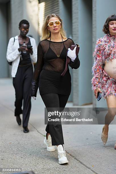 Guest wears shoulder-length blonde hair, oversized white-framed sunglasses with yellow lenses, gold drop earrings and a gold pendant necklace,...