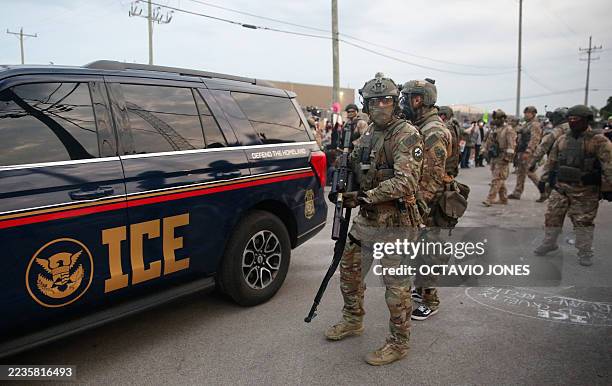 Immigration and Customs Enforcement agents armed with less-lethal weapons gather outside an ICE processing center during a protest in Broadview,...