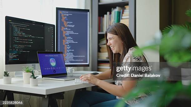 happy it specialist coding on dual monitors using ai virtual assistant - software development stock pictures, royalty-free photos & images