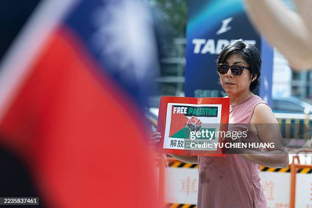 Woman displays a placard reading "free Palestine" denouncing Taiwan's defence industry ties with Israel during a protest outside the Nangang...
