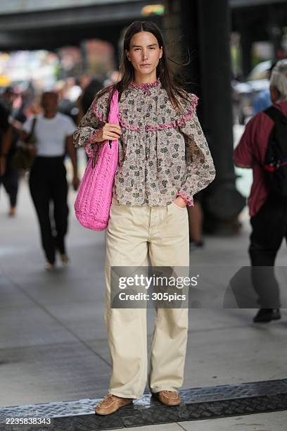 Mijo Mihaljcic is seen an Isabel Marant floral print blouse with pink ruffle trim, Madewell cream pants, Miu Miu moccasin suede shoes and carrying a...