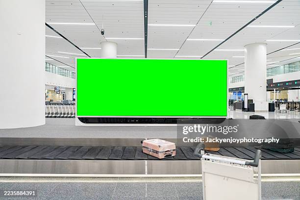 a green sign billboard is on a wall in a large airport - gewerbliches schild stock-fotos und bilder