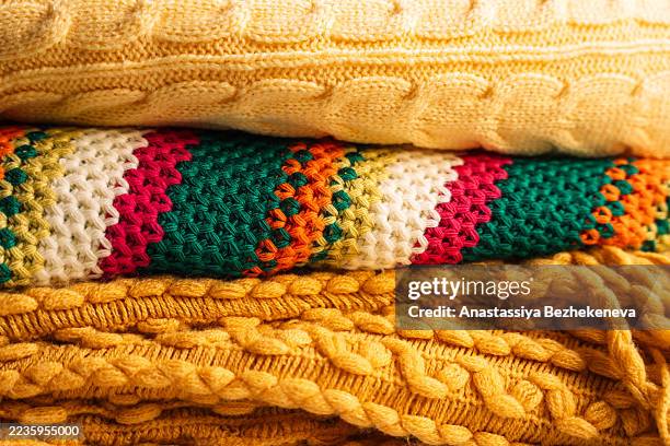 stack of knitted blankets and sweater in yellow and multicolor textures, close up - ribbed blanket stock pictures, royalty-free photos & images