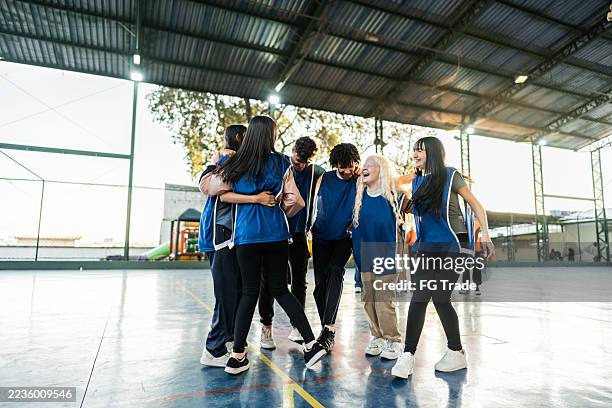 student team wearing blue vests celebrate on school sports field - physical education stock pictures, royalty-free photos & images