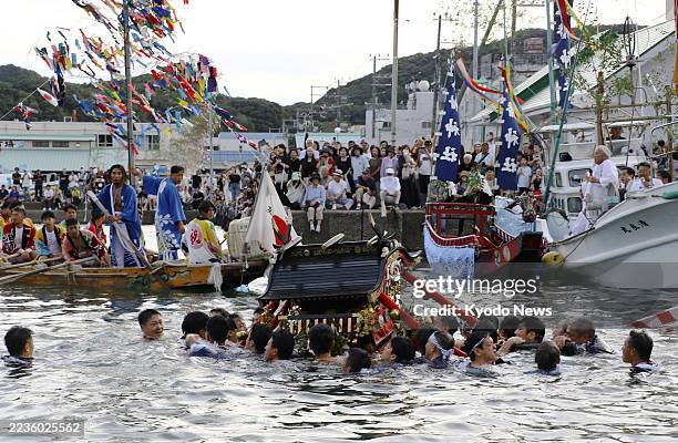 Men carrying a portable shrine participate in a water purification ceremony to pray for an abundant catch and maritime safety at Katsuura Hachiman...