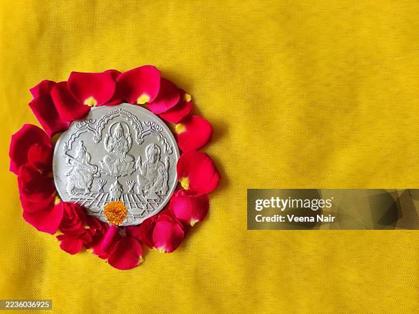 goddess lakshmi/saraswati/lord ganesh silver coin on a yellow silk cloth/ red rose flowers/navratri/diwali/dhanteras festival/copy space - déesse photos et images de collection