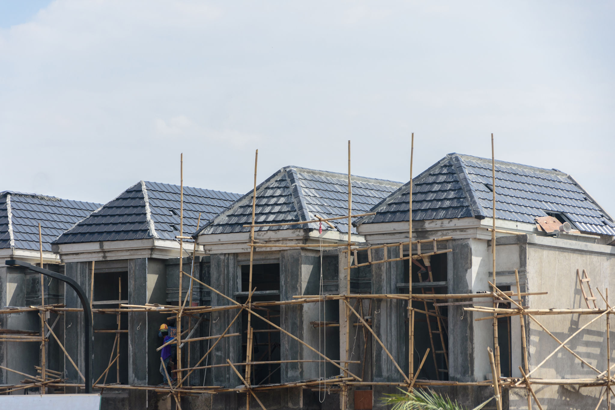 Row of new residential houses under construction with traditional bamboo scaffolding Row of new residential houses under construction with traditional bamboo scaffolding