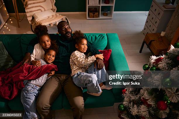 african american father and daughters watching tv at christmas - cosy christmas stock pictures, royalty-free photos & images