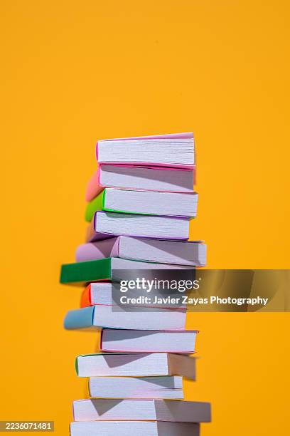 stack of colorful books balancing on orange background - paperback stock pictures, royalty-free photos & images