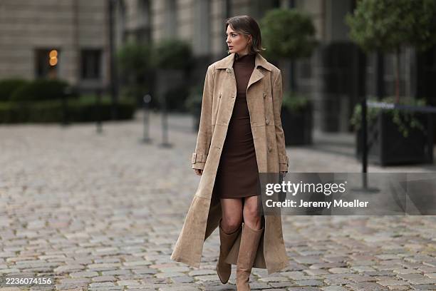 Yana Pries seen wearing a long suede leather trench coat from NOUR HAMMOUR in a warm beige tone. The coat features double-breasted buttons, a...