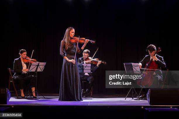 elegant quartet performing on stage with graceful violinist and string instruments - classical musician stock pictures, royalty-free photos & images