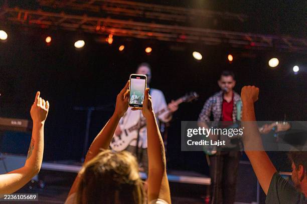 energetic live concert with enthusiastic crowd cheering and recording the performance - efeito de luz imagens e fotografias de stock