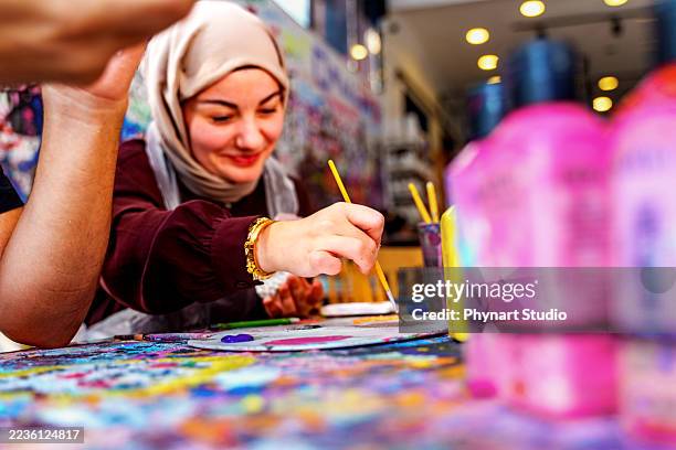 young woman painting ceramic craft at art studio, focusing on creativity and handmade design - stampot stockfoto's en -beelden