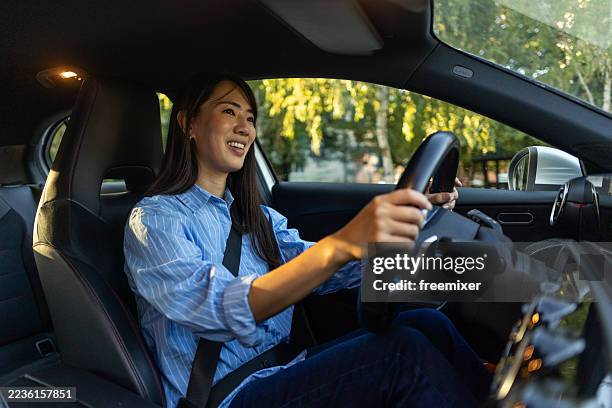 happy young woman driving a car through a scenic neighborhood - driverless car stock pictures, royalty-free photos & images