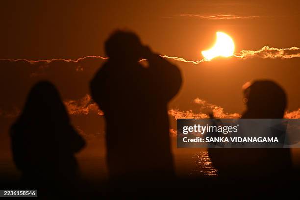 People watch a partial solar eclipse at New Brighton, a coastal suburb of Christchurch, on September 22, 2025. A solar eclipse occurs when the moon...