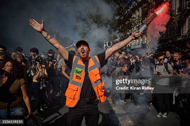 Member of the SUD Railway Union holds a flare aloft and chants as thousands of protesters march through central Paris during nationwide...