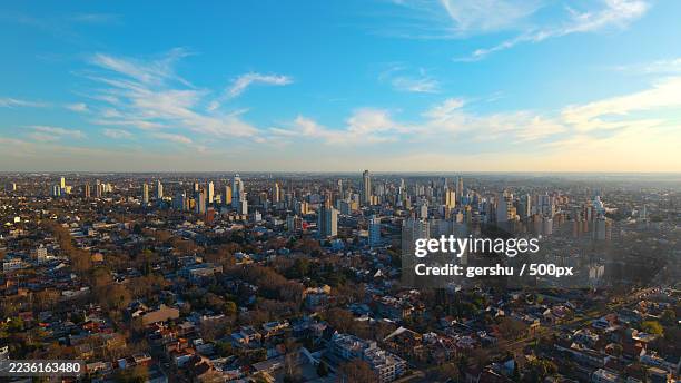 high angle view of a sprawling city with modern buildings under a vibrant blue sky with wispy clouds - la plata argentinien stock-fotos und bilder