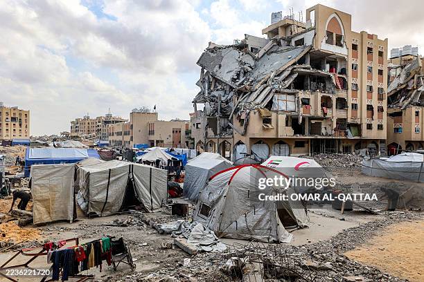 Tents sheltering Palestinians displaced by conflict from Gaza City are pitched by damaged buildings at the Qatari-built Hamad City residential...