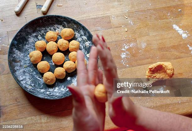 making pumpkin gnocchi from scratch on a wooden counter with a plate of ready-made gnocchi - gnocchi stockfoto's en -beelden