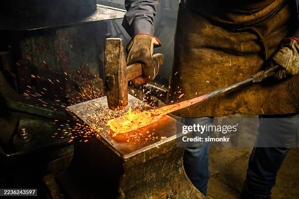 fabbro che forgia abilmente il metallo con il martello - fabbro ferraio foto e immagini stock