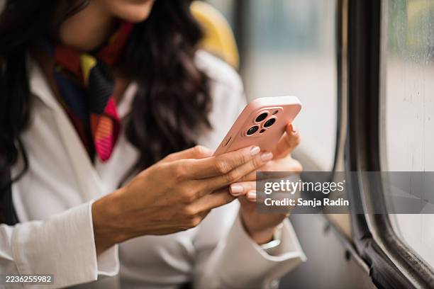 close-up of hands typing on smartphone by bus window - phone cover stock pictures, royalty-free photos & images