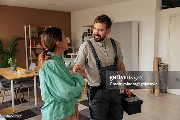 woman thanking handyman after repair - empreiteiro de reparações imagens e fotografias de stock