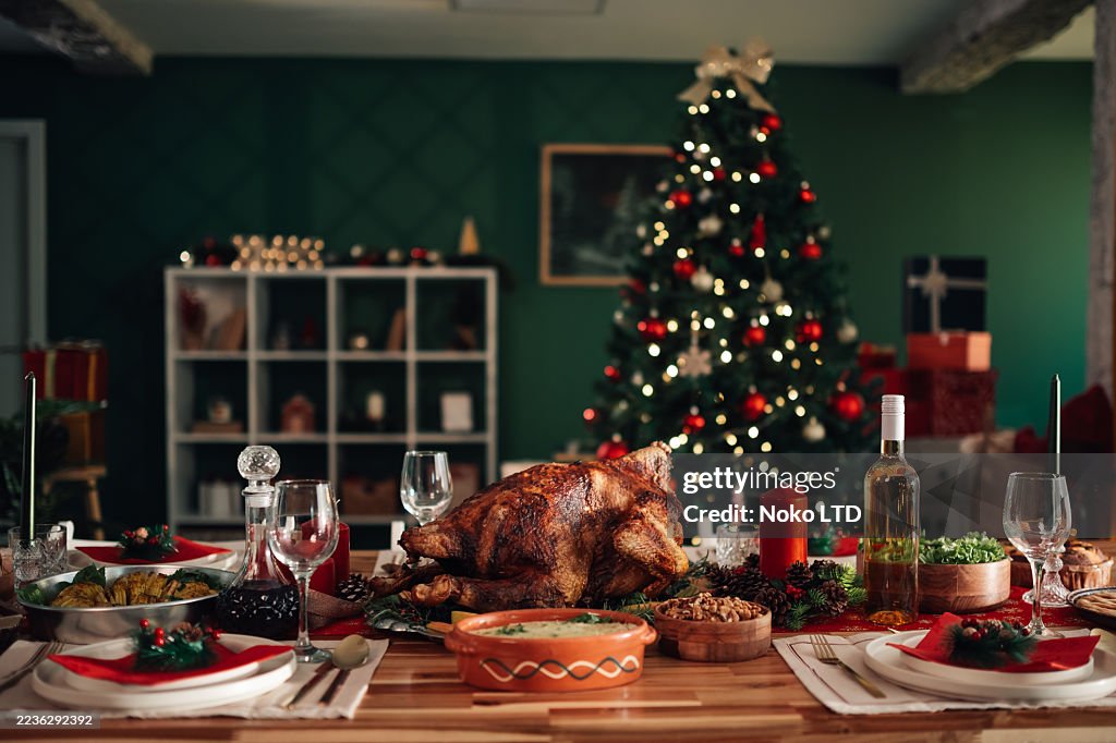 Christmas dinner table setting with roast turkey and festive decorations