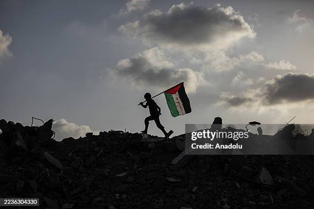 Group of Palestinian children in Bureyc Camp raise the Palestinian flag over the rubble of buildings destroyed by Israeli strikes following...
