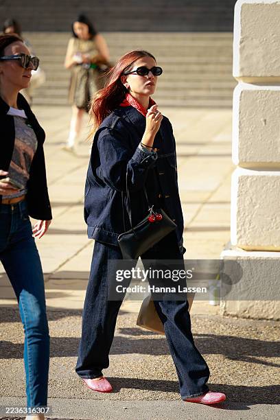 Guest wearing red scarf, denim jacket and pants, outside Fashion East during London Fashion Week on September 19, 2025 in London, England.
