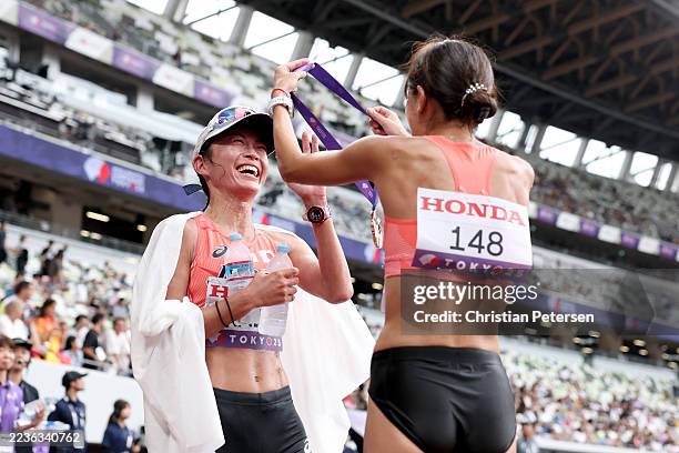 Silver medalist Nanako Fujii of Team Japan places her medal on teammate Kumiko Okada of Team Japan after the Women's 20 Kilometres Race Walk during...