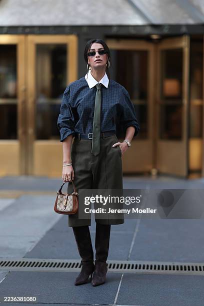 Marisa Lauren is seen wearing a dark blue plaid shirt with a crisp white collar, layered with a green tie that adds a preppy, structured element to...