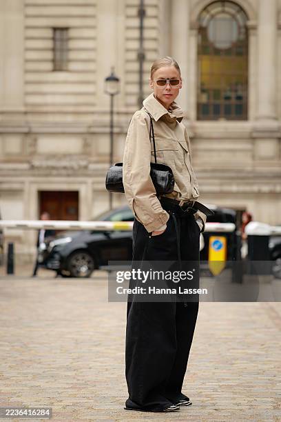 Guest wearing beige cropped jacket, black belt, black jeans, zebra patterned shoes and black bag outside TOGA during London Fashion Week on September...