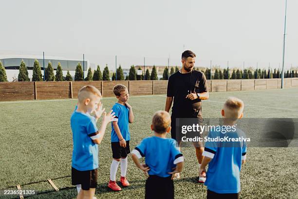 coach instructing junior football team - kids soccer stock pictures, royalty-free photos & images