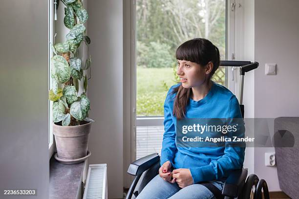 portrait of smiling neurodivergent teenage girl sitting by a window in wheelchair - developmental disability stock pictures, royalty-free photos & images