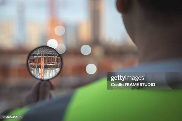 construction engineer uses magnifying glass to inspect steel framework, ensuring structural integrity, quality control and safety compliance on building site. - structural steel construction stock pictures, royalty-free photos & images