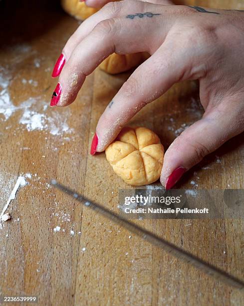 woman's hand crafting pumpkin-shaped gnocchi on a wooden cutting board for halloween - gnocchi stockfoto's en -beelden