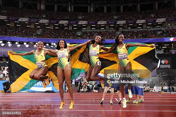 Silver medalists Nickisha Pryce, Stacey Ann Williams, Andrenette Knight and Dejanea Oakley of Team Jamaica celebrate with the national flags after...