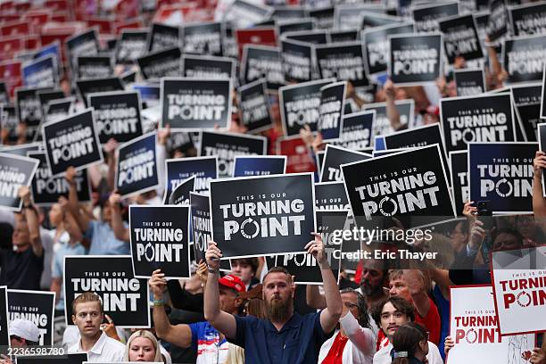 Attendees hold up Turning Point USA signs at the memorial service for political activist Charlie Kirk at State Farm Stadium on September 21, 2025 in...