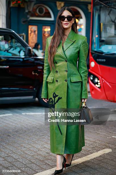 Olivia Munn wearing embellished double breasted leather coat, black leather bag with golden handle, black Saint Laurent sunglasses and black patent...